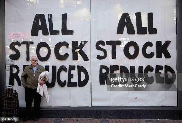 Man waits outside a shop displaying 'stock reduced' signs on December 22, 2008 in Swindon, England. Swindon has historically had a reputation as...