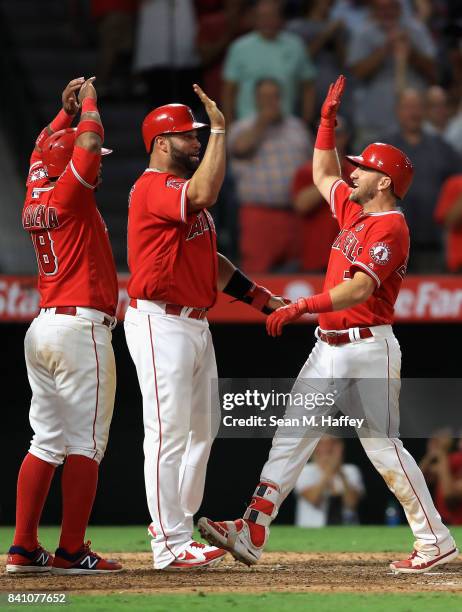 Luis Valbuena and Albert Pujols congratulate Cliff Pennington of the Los Angeles Angels at homeplate after he hit a grandslam homerun during the...