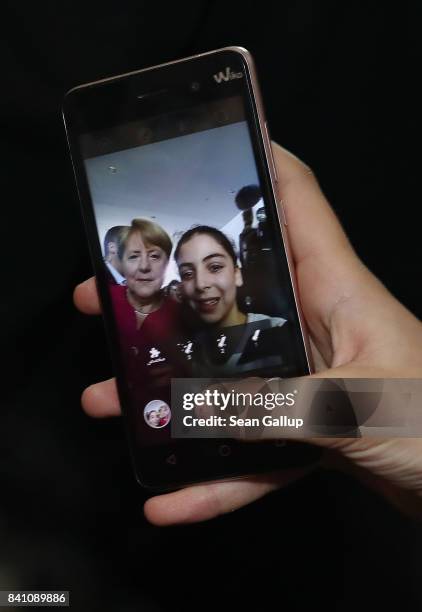 Young woman shoots a selfie with German Chancellor Angela Merkel on a smartphone during the annual open-house day at the Chancellery on August 27,...