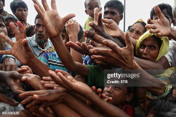 This August 30, 2017 photo shows Rohingya refugees reaching for food aid at Kutupalong refugee camp in Ukhiya near the Bangladesh-Myanmar border. The...