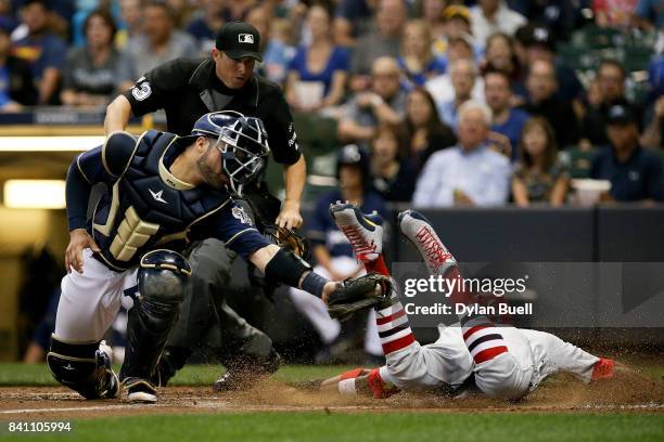 Dexter Fowler of the St. Louis Cardinals slides into home plate to score a run past Manny Pina of the Milwaukee Brewers in the third inning at Miller...