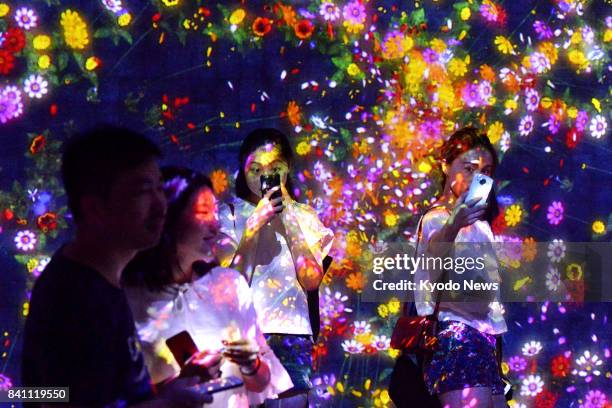 People visit an exposition, organized by a Japanese digital art group, in Beijing on Aug. 8, 2017. Visitors can see their drawings projected on a...