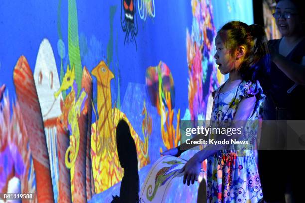 People visit an exposition, organized by a Japanese digital art group, in Beijing on Aug. 8, 2017. Visitors can see their drawings projected on a...