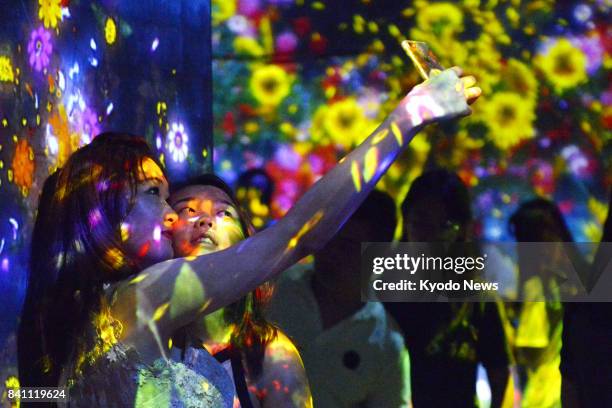 People visit an exposition, organized by a Japanese digital art group, in Beijing on Aug. 8, 2017. Visitors can see their drawings projected on a...