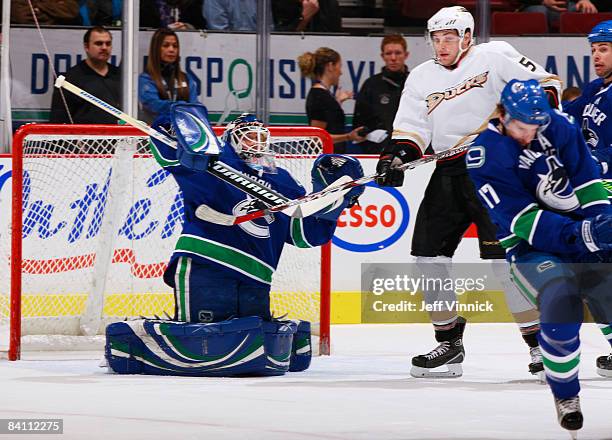 Ryan Kesler of the Vancouver Canucks blocks a shot in front of his goaltender Curtis Sanford with Steve Montador of the Anaheim Ducks at the top of...
