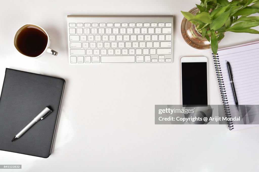 White office table top view with smart phone, computer keyboard copy space