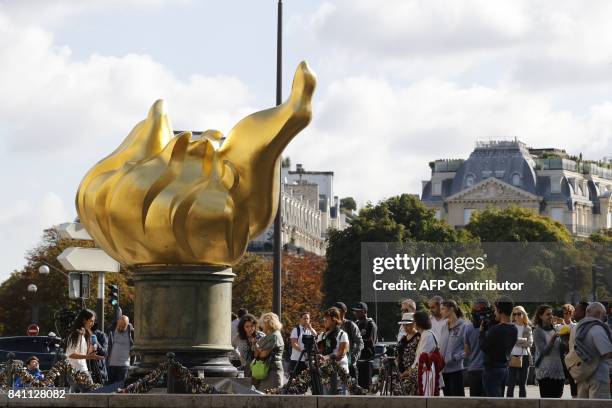 People look at flowers, messages and pictures laid around the Flame of Liberty monument - which became an unofficial memorial for Diana, Princess of...