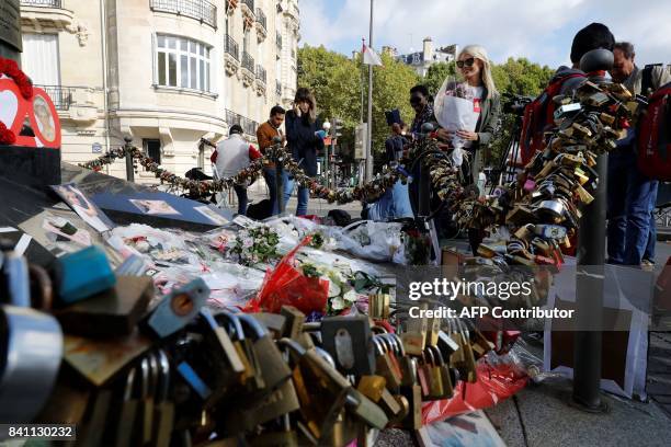 People look at flowers, messages, pictures and locks laid around the Flame of Liberty monument - which became an unofficial memorial for Diana,...