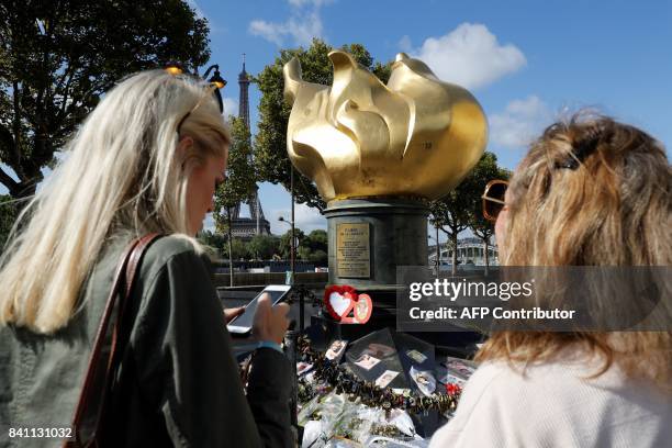 Women stand next to flowers, messages, pictures and locks laid around the Flame of Liberty monument - which became an unofficial memorial for Diana,...