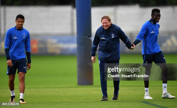 Douglas walks on as Head Coach Markus Gisdol grips Bakery Jatta during a training session of Hamburger SV on August 31, 2017 in Hamburg, Germany.