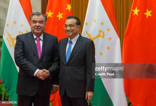 Chinese Premier Li Keqiang and Tajikistan's President Emomali Rahmon shake hands during their meeting at the Great Hall of the People in Beijing,...
