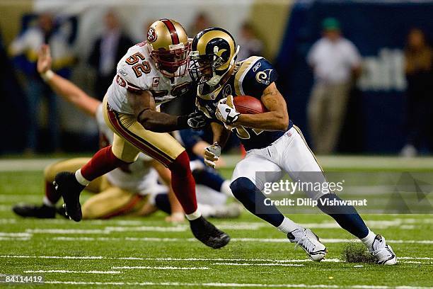 Torry Holt of the St. Louis Rams carries the ball against Patrick Willis of the San Francisco 49ers at the Edward Jones Dome on December 21, 2008 in...