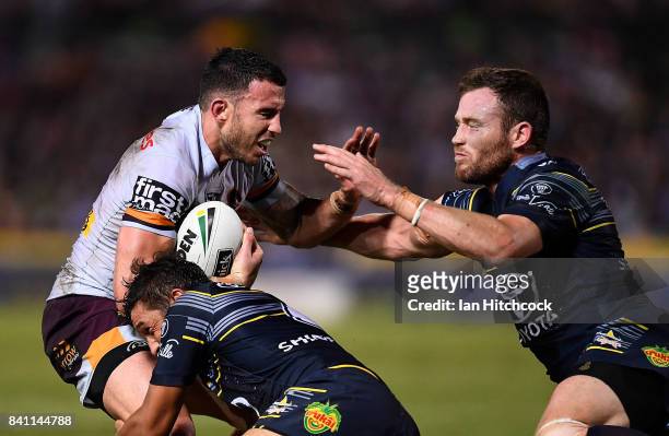 Darius Boyd of the Broncos is tackled by Gavin Cooper and Te Maire Martin of the Cowboys during the round 26 NRL match between the North Queensland...