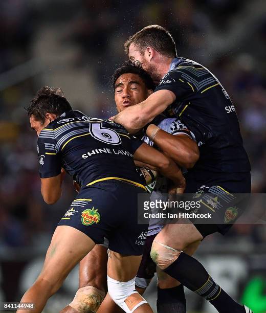 Joe Ofahengaue of the Broncos is tackled by Te Maire Martin and Gavin Cooper of the Cowboys during the round 26 NRL match between the North...