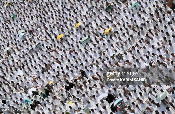Muslim worshipers, some carrying umbrellas to protect them from the scorching sun, gather for prayer at Namirah mosque near Mount Arafat, also known...