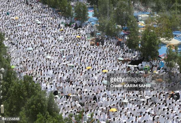 Muslim worshipers, some carrying umbrellas to protect them from the scorching sun, gather for the noon prayer at Namirah mosque near Mount Arafat,...