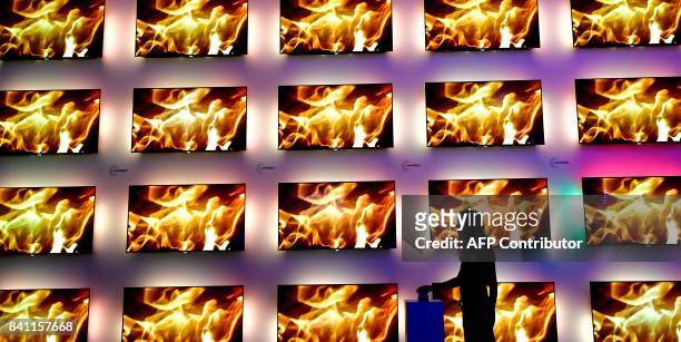 Fair worker stands next to an installation of televisions equipped with the ambilight lighting system developed by Philips at the IFA Consumer...