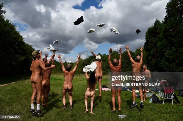 Graphic content / Naked people throw their clothes up in the air at a newly opened space for naturists at the Bois de Vincennes park in Paris on...