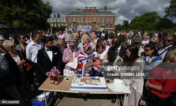 Royal fan John Loughrey hands out slices of a cake adorned with a picture of Diana, Princess of Wales, to members of the public who had gathered...