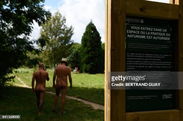 Graphic content / Two naked men walk past a sign reading "you are entering a space where the practise of naturism is authorised" at a newly opened...