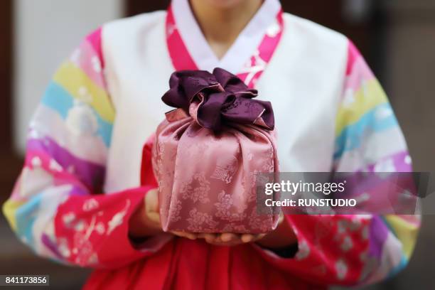 woman wearing a hanbok and holding traditional gift - chuseok stock pictures, royalty-free photos & images