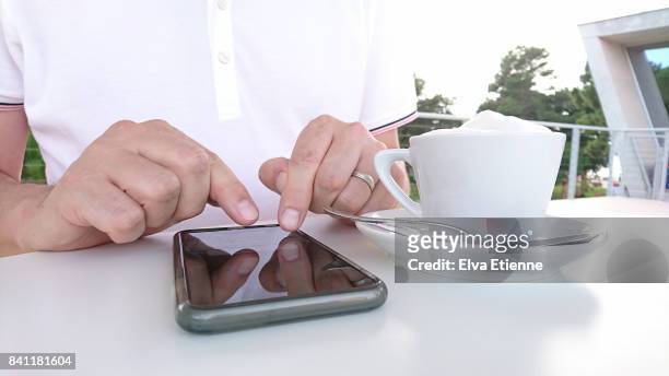 man using a smartphone and having a cappuccino - ウマグ ストックフォトと画像