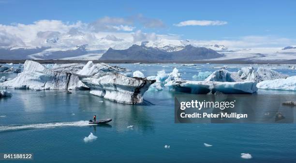 a rigid inflatable boat powers across the glacier lagoon at jokulsarlon, iceland - breidamerkurjokull glacier stock pictures, royalty-free photos & images