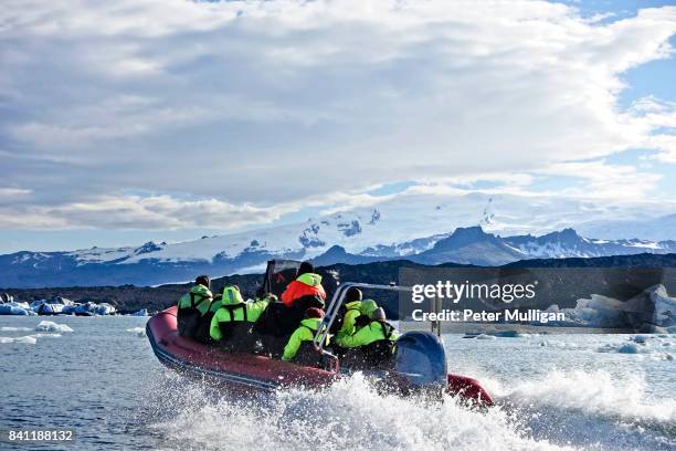 a rigid inflatable boat races across the glacier lake at jokulsarlon, iceland - jokulsarlon stock pictures, royalty-free photos & images