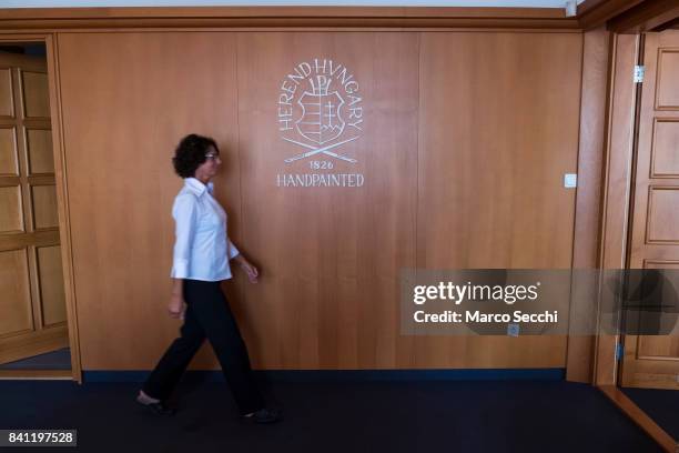 Member of staff at Herend Porcelain walks in front of the company logo on August 31, 2017 in Veszprem, Hungary. Herend Porcelain founded in 1826 is...