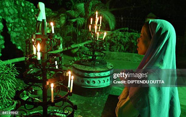 An Indian Christian woman prays after placing candles in front a statue of Jesus Christ at the St. Mary's Church in Siliguri on Christmas eve,...