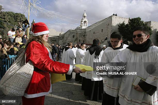 Woman wearing a Santa Claus outfit distributes leaflets to Palestinian clergymen outside the Church of the Nativity in the Biblical West Bank town of...