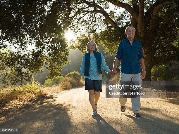 mature couple walking down dirt road - shorts down stock pictures, royalty-free photos & images