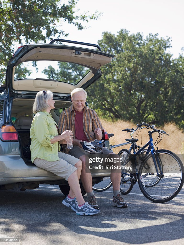 Mature couple sitting on back of car 