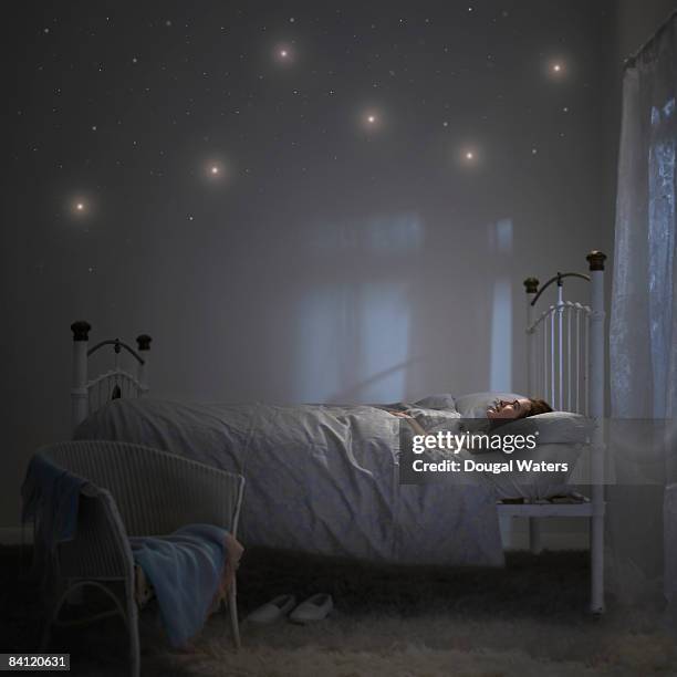 young woman in bed looking up at stars. - duvet stock pictures, royalty-free photos & images