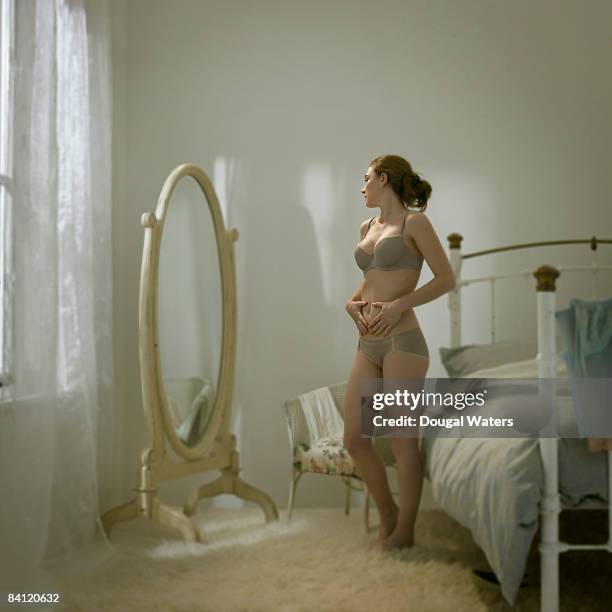 young woman in underwear looking in mirror. - full length mirror stock-fotos und bilder
