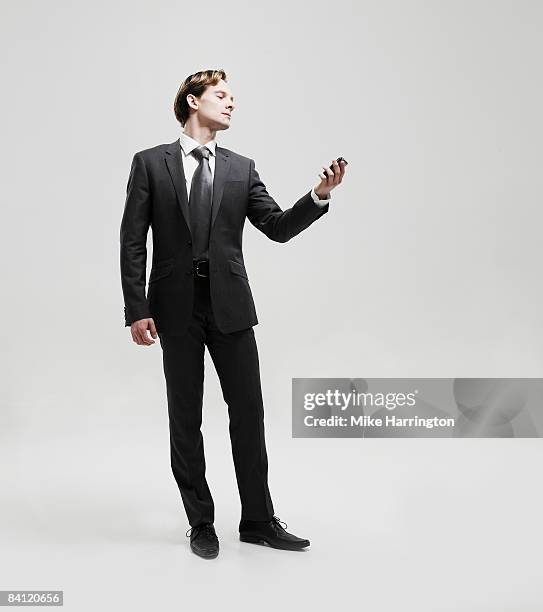 businessman looking at mobile phone - homme costume photos et images de collection