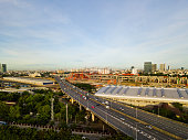 The morning call from sunrises with the aerial view of cars travel on highway and the country infrastructure of new train station in Bangkok city, Thailand