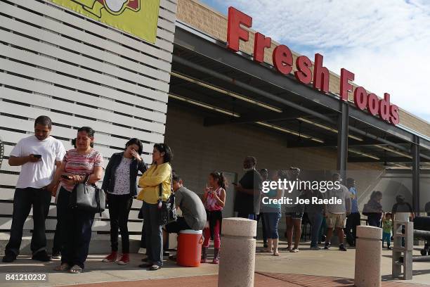 People wait in line in hopes of buying water at a grocery store after the water supply to the city of Beaumont was shut down after Hurricane Harvey...