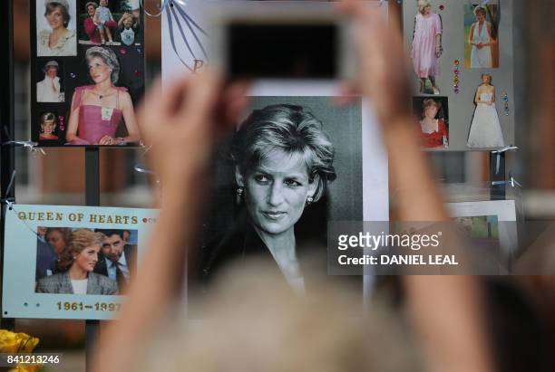 Members of the public gather at the tributes of flowers, candles and photographs outside one of the gates of Kensington Palace in London on August 31...