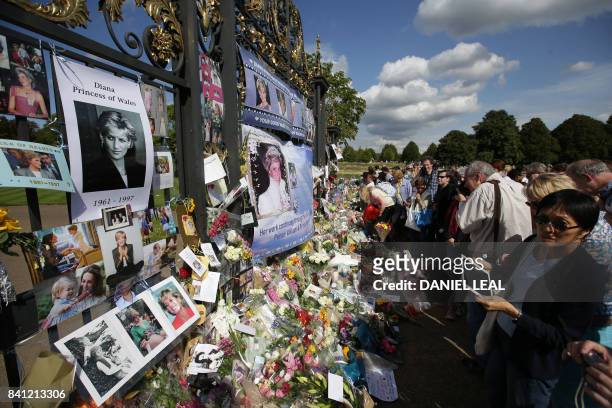 Members of the public gather at the tributes of flowers, candles and photographs outside one of the gates of Kensington Palace in London on August 31...