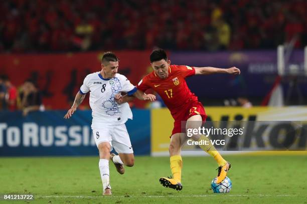 Li Xuepeng of China and Server Djeparov of Uzbekistan compete for the ball during the 2018 FIFA World Cup qualifier game between China and Uzbekistan...