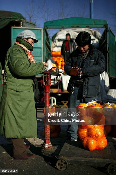 Vendor sells fruits to a customer at the Xinfadi Fruit Wholesale Market on December 25, 2008 in Beijing, China. Inflation dropped to a 22-month low...