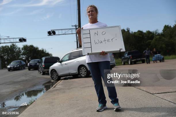Barbara Nelson from Coastal Industrial and Specialty gas welding supplies store holds a sign that reads, 'no water', after they ran out of bottled...