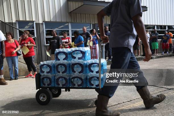 People wait in line to buy water at the Coastal Industrial and Specialty gas welding supplies store after the water supply to the city of Beaumont...