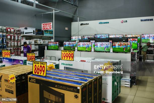 Customers browse smart flat screen televisions on display inside a HiFi Corp. Store, operated by Steinhoff International Holdings NV, in Pretoria,...