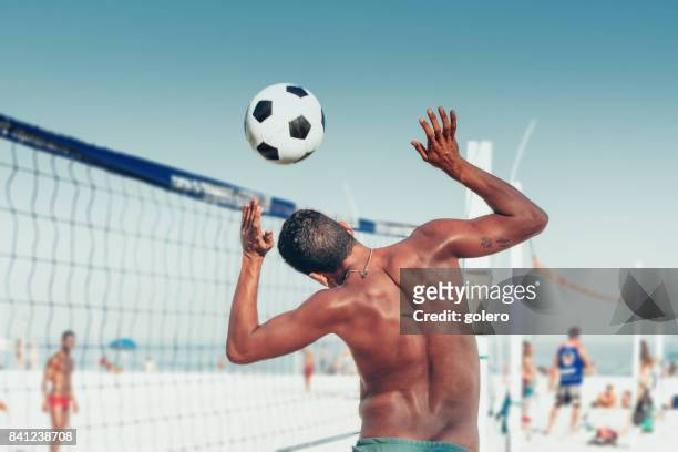 brasilianischen mann überschrift soccerball über volleyballnetz am strand - bundesstaat rio de janeiro stock-fotos und bilder