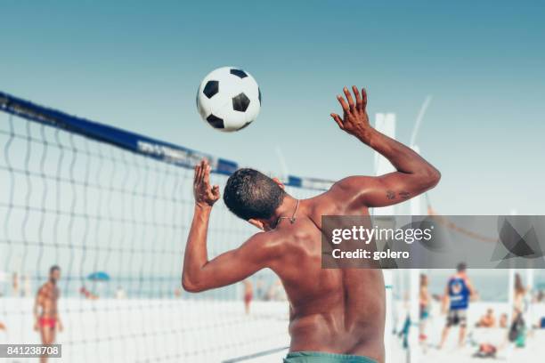 braziliaanse man kop soccerball over volleybal net op strand - deelstaat rio de janeiro stockfoto's en -beelden