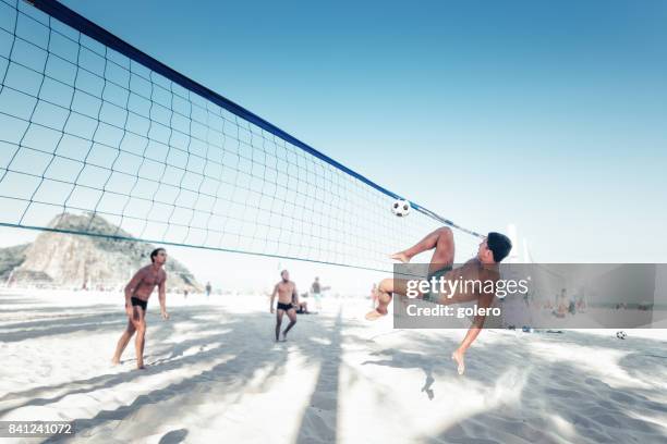 brazilian man kicking soccerball over volleyball net in rio - beachvolleyball stock pictures, royalty-free photos & images