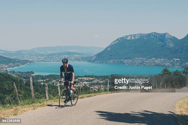 senior male cycling near lake annecy - lac d'annecy photos et images de collection