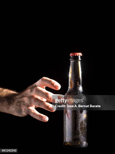 bottle of beer with the glass esmerilado with drops of water and the hands of a man grab  on a black background - beer mat stockfoto's en -beelden